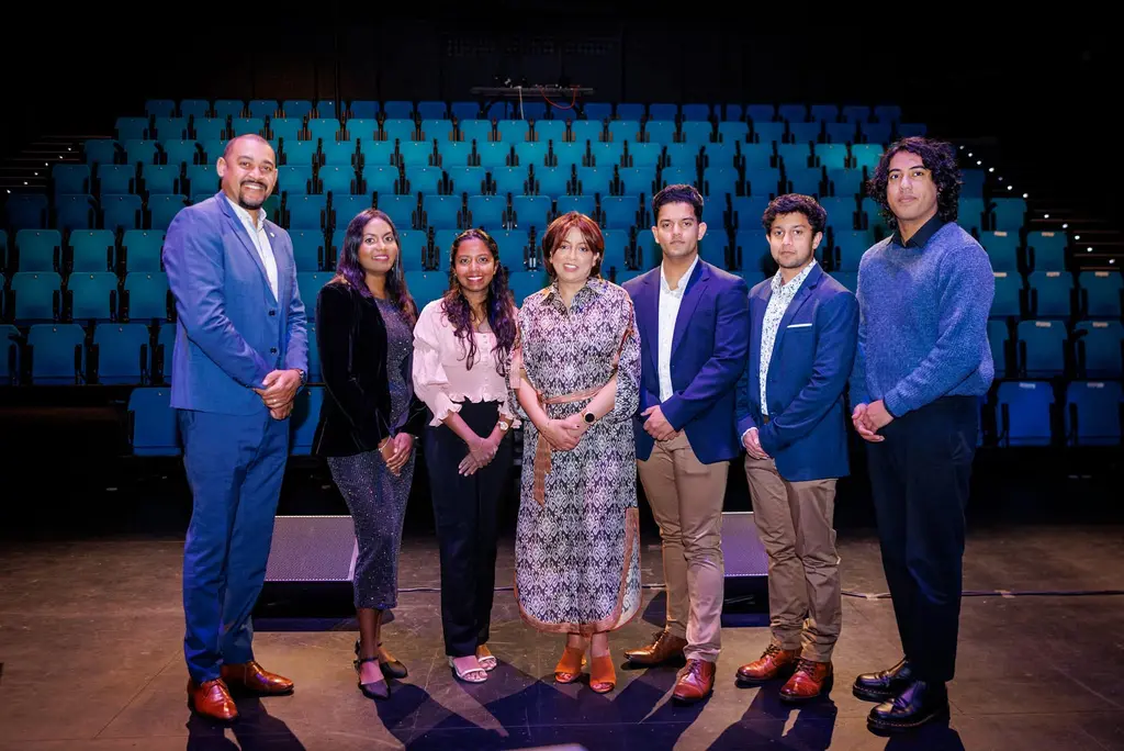 staff from Musical Minds Studio proudly standing in front of the camera in a theatre venue