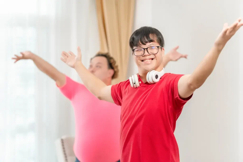 two young adults with Down syndrome smiling and enjoying a group dance and music class